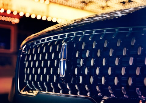 The Corsair Grand Touring grille shows floating chrome ovals that catch the glowing light of a theater marquee and frame the distinctive Lincoln Star | Performance Lincoln Bountiful in Bountiful UT