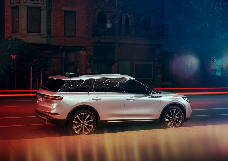 A 2022 Lincoln Corsair SUV is parked near a theater at night as the bright lights of a marquee dance across the dark windows and curvature of the body | Performance Lincoln Bountiful in Bountiful UT