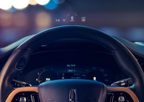The available head-up display projects data on the windshield above the steering wheel inside a 2022 Lincoln Corsair as the driver navigates the city at night | Performance Lincoln Bountiful in Bountiful UT